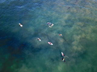 Aerial view of surfers waiting, paddling and enjoying the big waves before sunset time in Laguna...