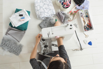 Tailor, fashion and seamstress concept - young female fashion designer in her showroom, top view
