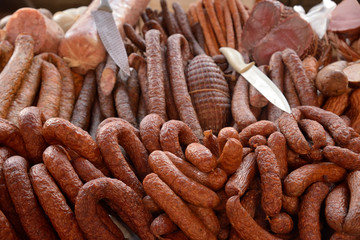 Many varieties of sausage on counter with knives