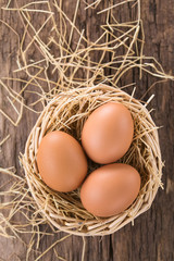 Fresh raw brown eggs on hay in basket, photographed overhead (Selective Focus, Focus on the top of the eggs)