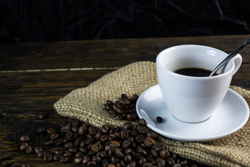 Cup of coffee and coffee beans on a rough wooden background.