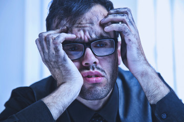 Tired, frustrated handsome man looking exhausted while sitting at his working place.