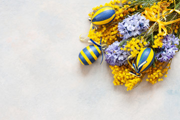 Easter decoration with Easter eggs, mimosa and hyacinths. Top view, close up, flat lay on sky blue background
