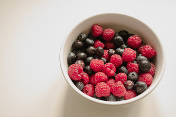 fresh berries and blueberries in a bowl isolated on white