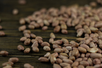 Raw peanuts on a rough wooden background.