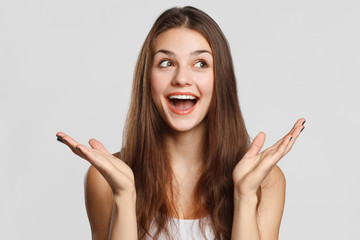 Surprised happy woman looking sideways in excitement, isolated on gray background