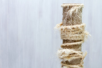 used scratching post with torn ropes, old cat tree on white background, copy space for text