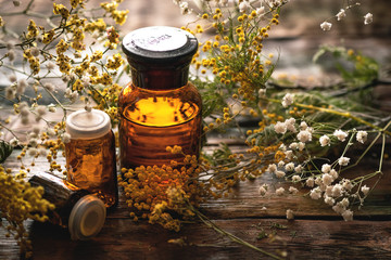 Wild flower essential oil bottle on a wooden board background. Herbal medicine.