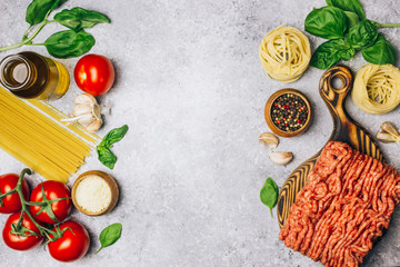 Bolognese pasta cooking concept: raw minced meat, tomatoes, pasta, parmesan, garlic, basil, olive oil