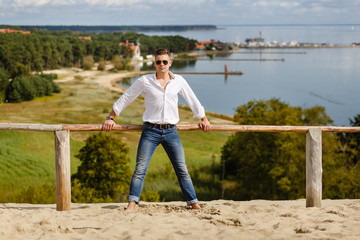 Portrait of a stylish guy on the slope against the backdrop of the sea