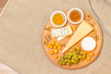 Assorted cheeses on round wooden board plate