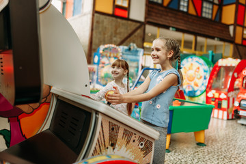 Two little girls plays on video game machine