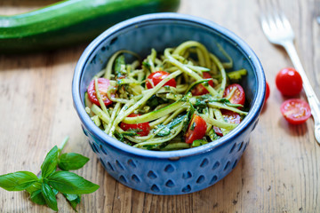 Zucchini spaghetti with rough basil and walnut pesto and cherry tomatoes