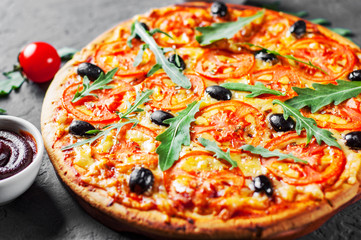 Pizza with Mozzarella cheese, Tomatoes, pepper, olive, Spices and Fresh arugula. Italian pizza. Pizza Margherita or Margarita on Dark grey black slate background
