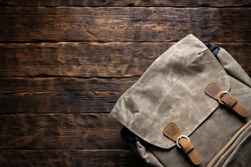 Travel or adventure flat lay background with copy space. A backpack on a brown wooden table.
