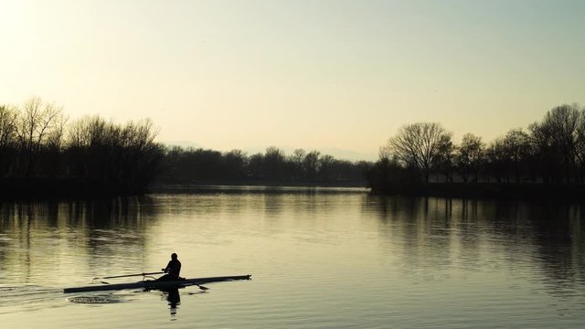 Image of man rowing alone at an artificial lake during sunset, Zagreb, Croatia.