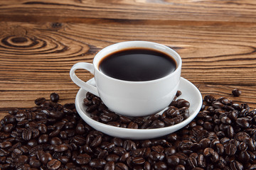 Fototapeta premium Hot coffee with hot steam and coffee beans on wooden table