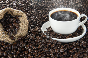 Hot coffee with hot steam and coffee beans on wooden table