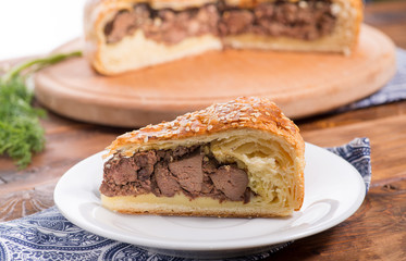 piece of Savory pie with filling on a wooden background with vegetables. Savory pie with filling.