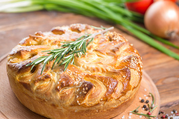 savory pie with a filling on a wooden background with vegetables