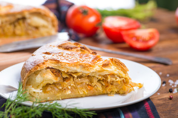 piece of Savory pie with filling on a wooden background with vegetables. Savory pie with filling.
