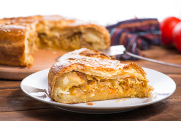 piece of Savory pie with filling on a wooden background with vegetables. Savory pie with filling.