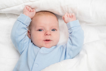 Portrait of a cute baby lying down on a bed. Baby on white cloth lying on his back