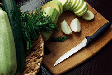 fresh zucchini and cucumbers in a basket near the cutting Board