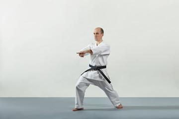 Adult male athlete performs formal karate exercises on a gray cover