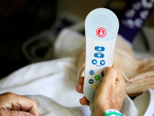 Old man holding TV remote with nurse call button