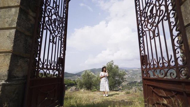 View through rust entrance gates young lady going on courtyard of traditional country house in valley of Douro river in winemaking region in Portugal