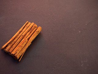 Several dried cinnamon sticks on a slate plate