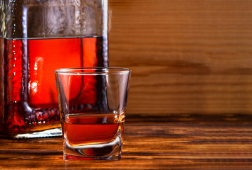glass with alcohol drink and bottle on wooden background