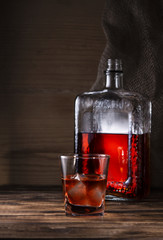 glass of whiskey with bottle on wooden background