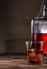 glass with alcohol drink and bottle on wooden background