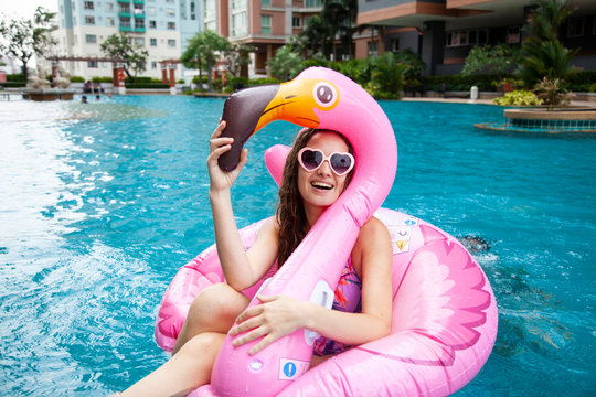 Sexy Girl Sunglasses Having Fun In The Pool Floating On A Large Inflatable Pink Flamingo In A Hotel On Summer Vacation