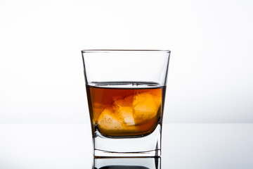 glass of whiskey or cognac with ice over white background