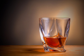 glass of whiskey or cognac over wooden table