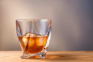 glass with drink and ice on wooden table