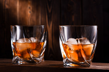 two glasses of whiskey or cognac over wooden background