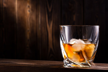 glass with drink and ice on wooden background