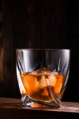 glass with drink and ice on wooden background