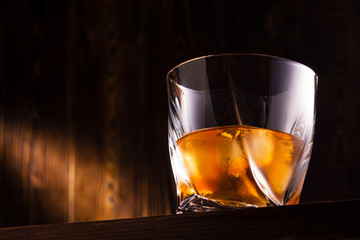 glass with drink and ice on wooden background