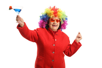 Cheerful senior woman with a colorful wig and a cocktail