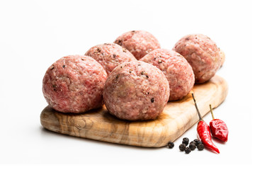 Raw meat balls on wooden cutting board isolated on white