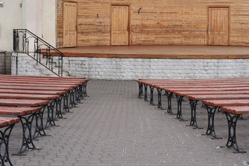 photograph of benches located in the future. benches are made of wood, they are brown. In the background of the stage and the stairs to the entrance to the stage