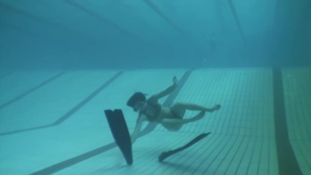 Girl freediver dress fins and shows ok underwater in swimming pool. Freediving training with flippers.