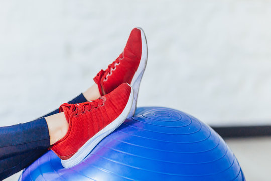 Photo of sporty red sheakers on blue fitness ball.