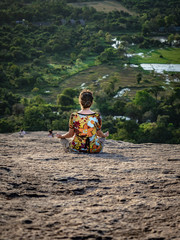 Young caucasian woman sitting and meditating on the top of the Rock Pidurangala. Sri Lanka, March 10, 2019.