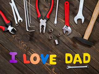 Happy Father's Day inscription with work tools on wooden background.